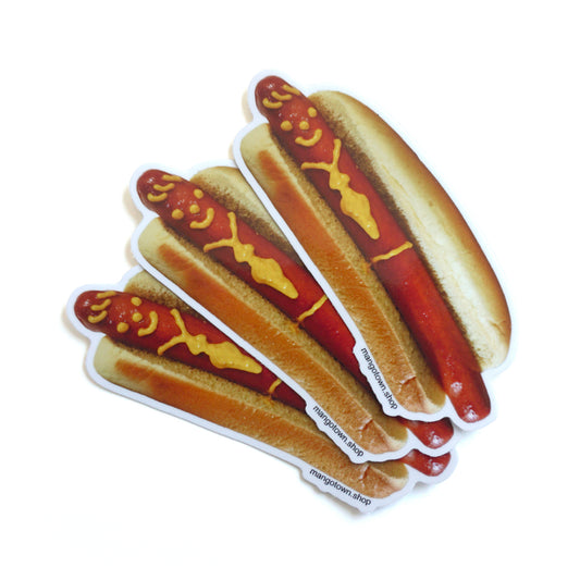 Photo of 3 die cut stickers of a hotdog with a smiley face and tie drawn on with mustard on a white background